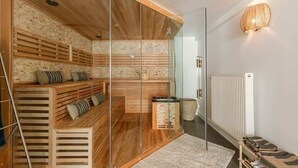 Ein modernes Badezimmer mit Duschkabine aus Glas, Holzbanken und Handtuchwärmer.