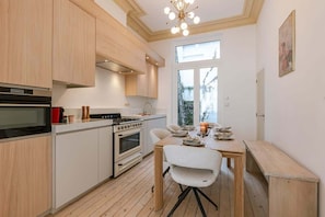 Una cocina moderna con armarios de madera, horno empotrado y comedor con mesa y sillas.