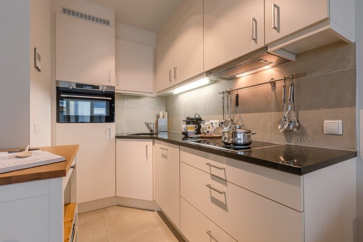 A modern kitchen with white cabinets, a black countertop, and stainless steel appliances.