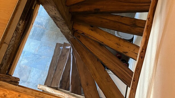 A wooden staircase with a view of a stone wall and a window. - Holiday Home 'Gite Les 4 Saisons' with Mountain View, Private Terrace and Wi-Fi (Val de Chaise)