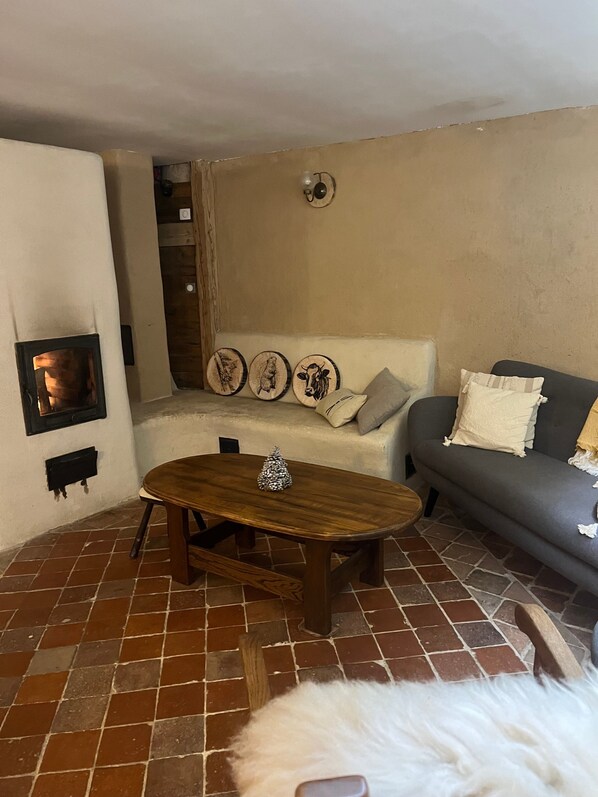 A living room with a fireplace, a sofa, a coffee table, and a dog. - Holiday Home 'Gite Les 4 Saisons' with Mountain View, Private Terrace and Wi-Fi (Val de Chaise)
