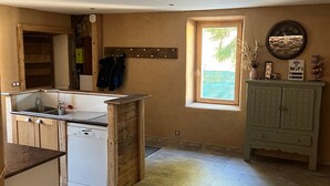 A kitchen with a dishwasher, wooden cabinets, a window, and a clock on the wall. - Holiday Home 'Gite Les 4 Saisons' with Mountain View, Private Terrace and Wi-Fi (Val de Chaise)