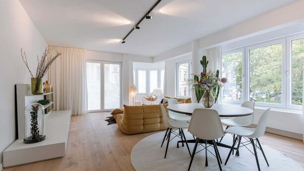 A modern living room with a dining area, large windows, and a view of greenery outside. - Family-ready apt w/ game console - heart of Ostend (Oostende)
