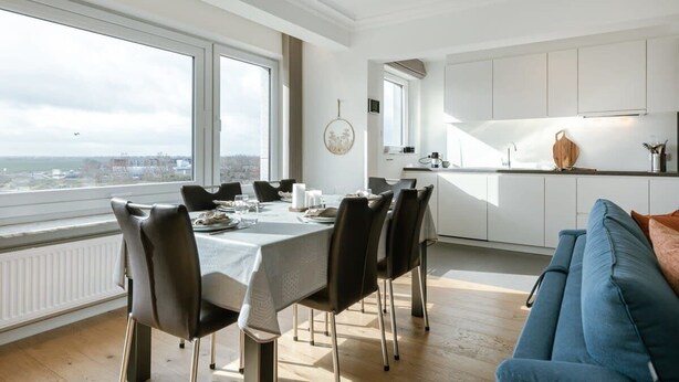 Een eetruimte met een tafel voor vier personen, een bank en uitzicht op de stad.