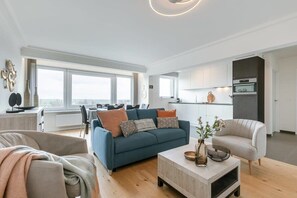 Ein modernes Wohnzimmer mit einer Couch, einem Couchtisch und einem Essbereich mit Stühlen.