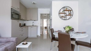 Una cocina moderna con zona de comedor, un sofá y una estantería de pared.