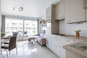 Eine moderne Küche mit Essbereich, großen Fenstern und einer Couch.