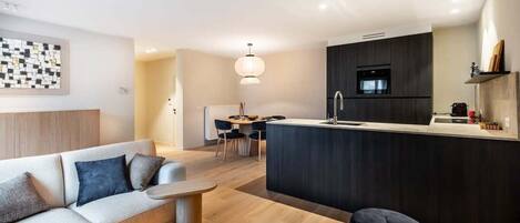 Una sala moderna con sofá, mesa de comedor y área de cocina con barra.