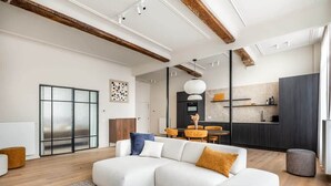 Una sala de estar moderna con un sofá modular, una mesa de centro redonda y un comedor con sillas amarillas.