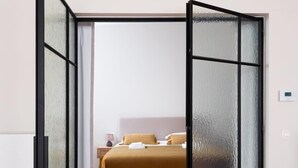 Una habitación con cama, un radiador blanco y un panel de vidrio esmerilado.