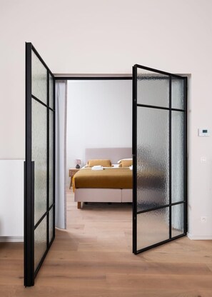 A room with a bed, a white radiator, and a frosted glass partition. - Historic retreat w/ self check-in (Gent)