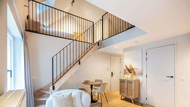 A modern interior with a staircase, a sofa, a dining table, and a cabinet. - Duplex studio near Ghent's centre (Gent)