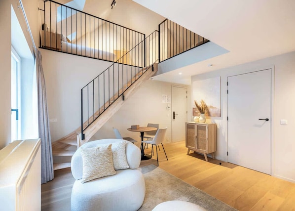 Un intérieur moderne comprenant un escalier, un canapé, une table à manger et un meuble.