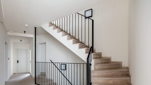 Eine Treppe mit schwarzem Geländer, beigen Stufen und einer weißen Wand.