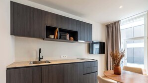 Eine moderne Küche mit dunklen Holzschränken, einem eingebauten Ofen und einem Essbereich mit rundem Tisch und Stühlen.