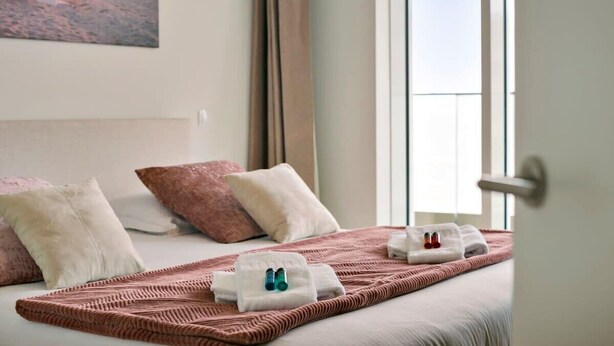 Ein Hotelzimmer mit einem Bett, Kissen, einer Decke und einem Handtuch sowie Flaschen.