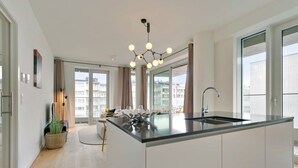 Eine moderne Küche mit einer zentralen Kochinsel, großen Fenstern und einer hängenden Leuchte.
