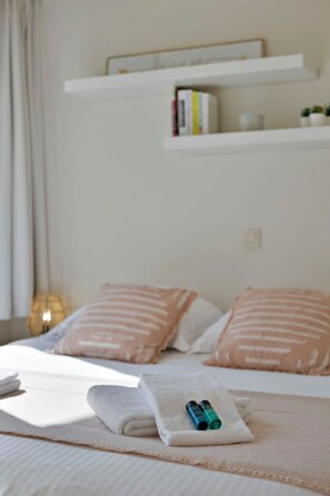 A neatly made bed with pillows, a folded towel, and two bottles on a bedside table. - Cozy apartment w/ balcony & parking (Knokke-Heist)