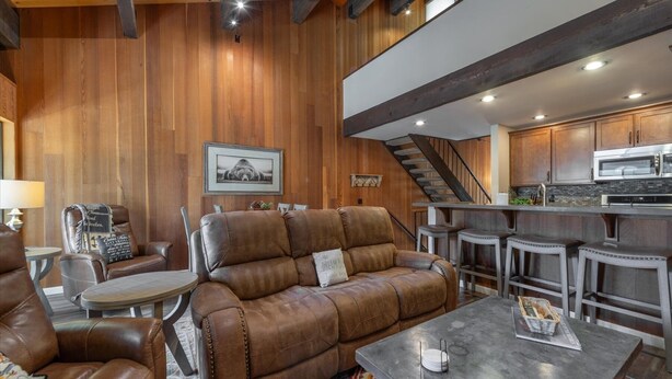A cozy living area with a leather sofa, a small round table, and a kitchen in the background. - Kingswood Village 57 3 Bedroom Condo (Kings Beach)