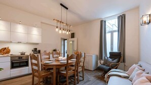 A modern kitchen with white cabinets, a dining table with chairs, a built-in oven, and a refrigerator. - 3BR apartment w/ kitchen (Gent)