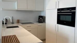 Eine moderne Küche mit weißen Schränken, einem eingebauten Ofen und einer Kaffeemaschine.