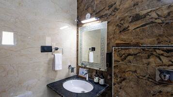 A bathroom with a marble sink, a mirror with a decorative frame, a towel rack, and a hand dryer.