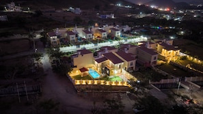 A residential area with houses, a swimming pool, and a well-lit entrance. - ELIVAAS Casa llios Stuning Getaway Villa (Udaipur)