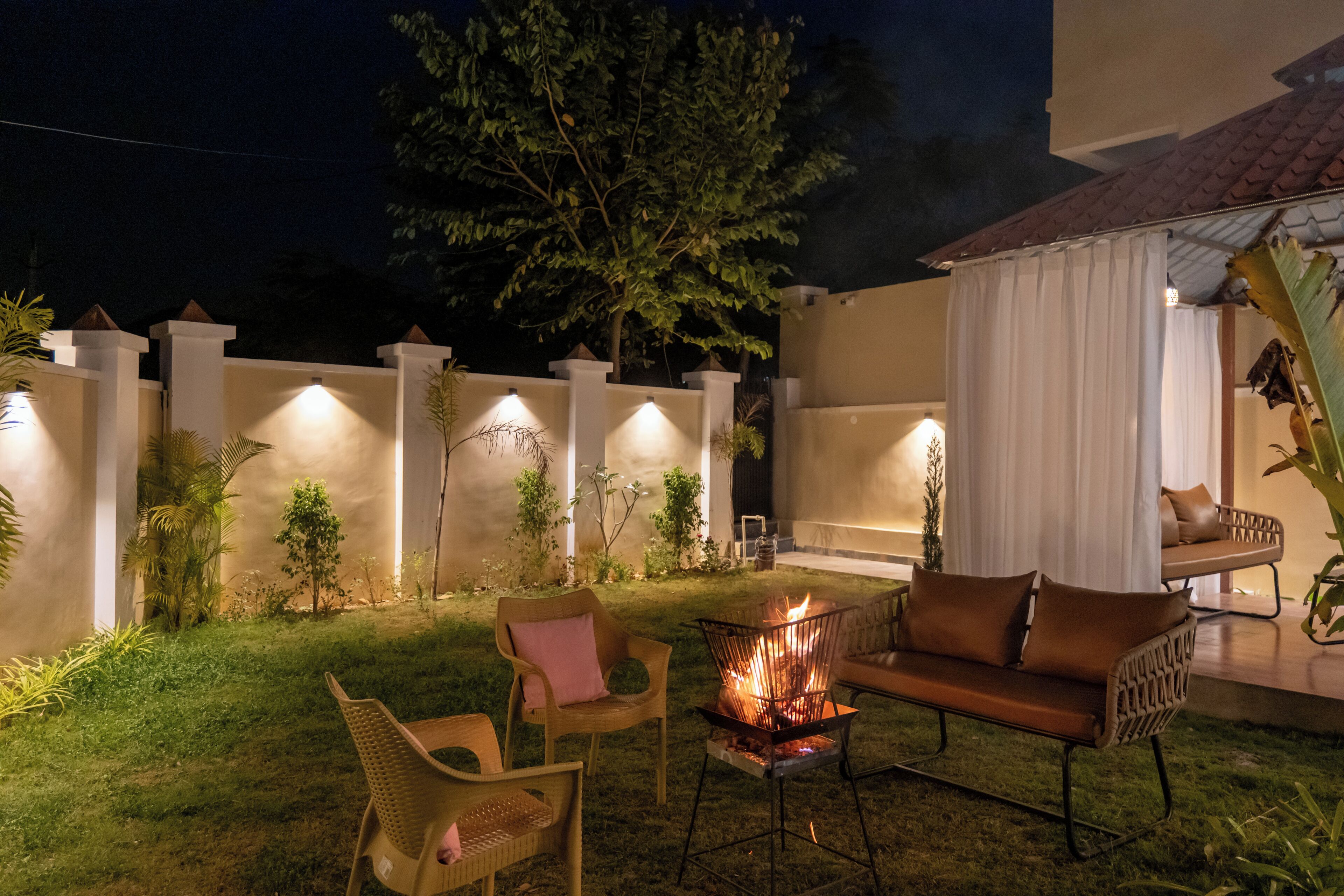 Un espacio al aire libre con un hogar para fuego, sillas y un sofá.