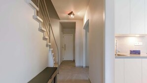 Um interior moderno com uma escada, um banco e uma área de cozinha.