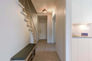 Un intérieur moderne avec un escalier, un banc et un coin cuisine.