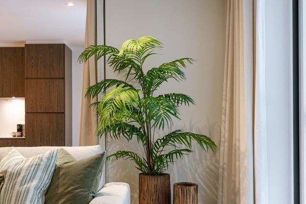 Modern living room corner with a light sofa, green cushions, and decorative wooden planters.