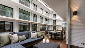 Eine moderne Hotelhalle mit großzügiger Sitzecke, einem Esstisch und einer Treppe zu den oberen Etagen.