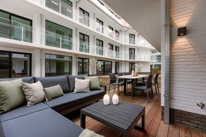 Eine moderne Hotelhalle mit großzügiger Sitzecke, einem Esstisch und einer Treppe zu den oberen Etagen.