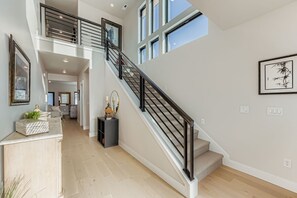 A spacious interior with a staircase, wooden floors, and framed artwork. - Luxurious 4-Bedroom RetreatClose to Deer Valley East Village 1936 4 Home (Heber City)