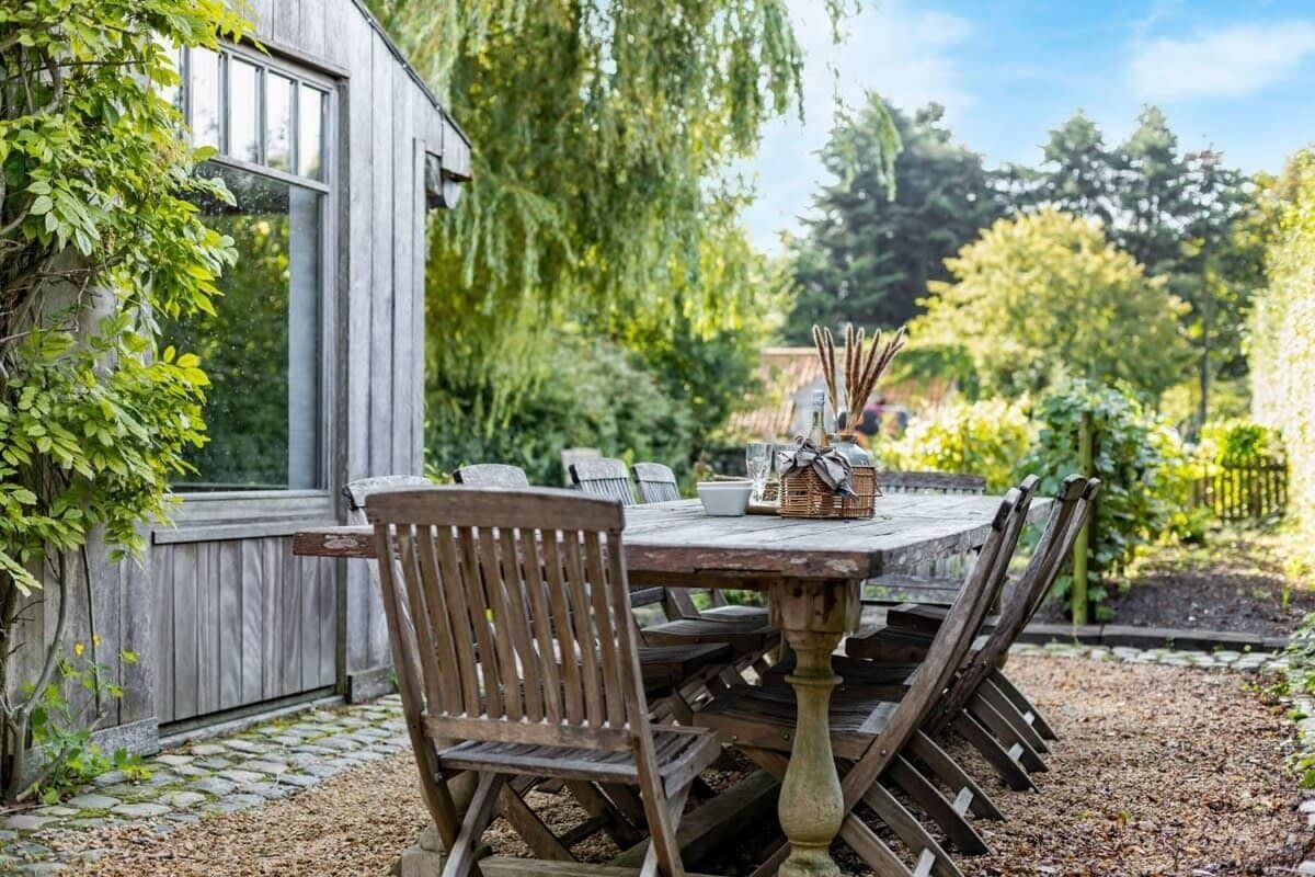 A wooden table with chairs, a basket, and a window overlooking a garden.