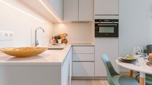 A modern kitchen with a large island, built-in oven, and a dining area with a round table and chairs. - Coastal retreat w/ terrace & self check-in (Oostende)