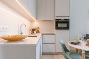 Una cocina moderna con una isla grande, horno empotrado y un área de comedor con una mesa redonda y sillas.