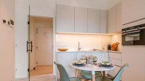 A modern kitchen with white cabinets, a dining table with teal chairs, and an oven. - Coastal retreat w/ terrace & self check-in (Oostende)