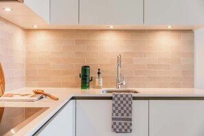 Een keuken met een spoelbak, kraan en een groen apparaat.