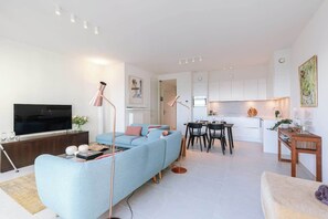 Een moderne woonkamer met een bank, televisie en een eethoek.