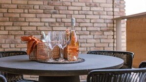 Una mesa redonda con una botella, vasos y una cesta tejida con tela.