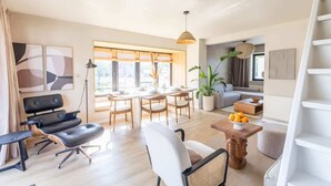 Una sala de estar moderna con comedor, un sofá, una mesa de centro con fruta y una escalera.