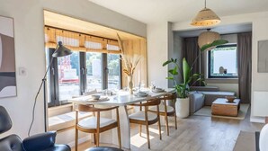 Una sala de estar moderna con comedor, ventanas amplias y vistas al exterior.