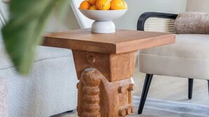 Una mesa de madera con un cuenco de naranjas, sobre una alfombra texturizada.