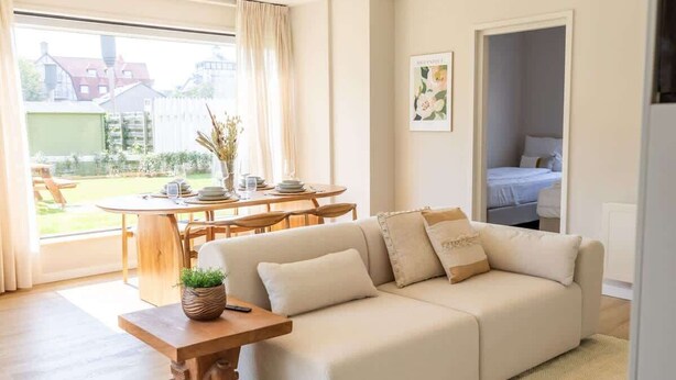 Un salon moderne avec un canapé, une table à manger et une vue sur l’extérieur.