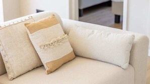 Un canapé beige agrémenté de deux coussins, dont l’un présente un motif texturé et l’autre est uni.