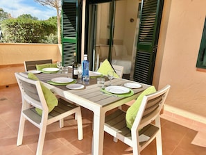 A table set for four with white plates, green napkins, and a bottle of wine.