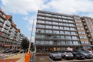 Un immeuble à plusieurs étages doté d’une architecture moderne, avec des balcons et de grandes fenêtres.