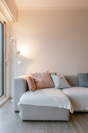 Un salon moderne avec un canapé, des coussins, une lampe sur pied et une fenêtre.