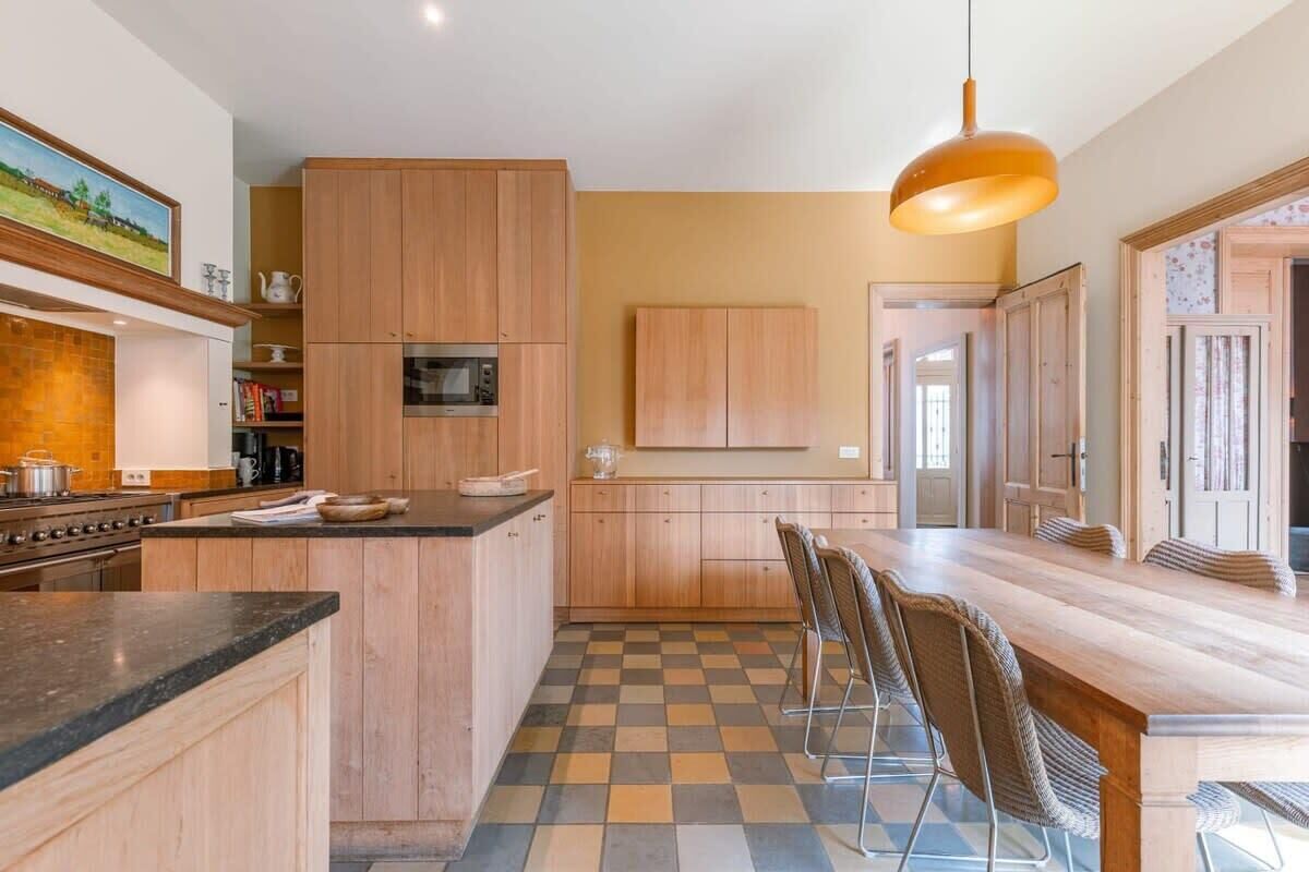 A kitchen with wooden cabinets, a central island, and a checkered floor.